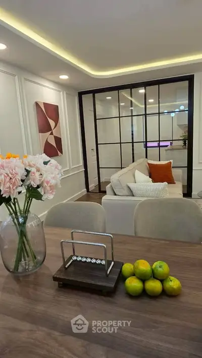 Modern living room with elegant decor and cozy seating area, featuring stylish wall art and fresh flowers.