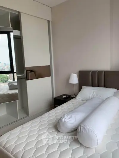 Modern bedroom with stylish bed and mirrored wardrobe, city view from window.