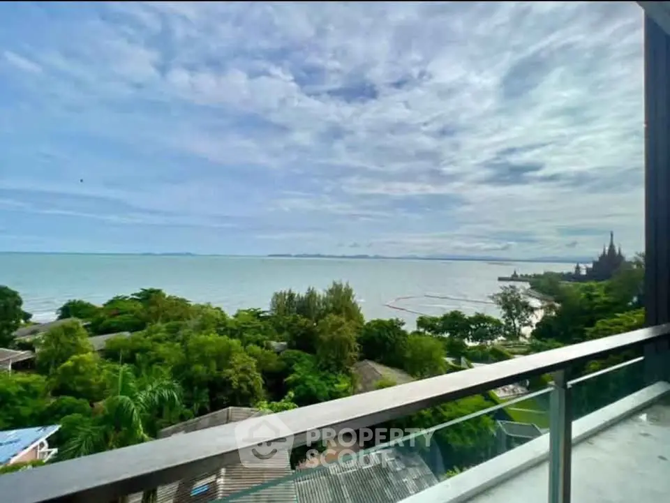 Stunning ocean view from a high-rise balcony overlooking lush greenery and serene coastline.