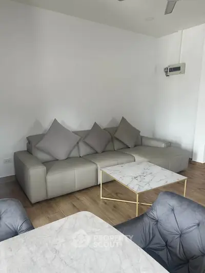 Modern living room with stylish marble table and comfortable gray sofa.