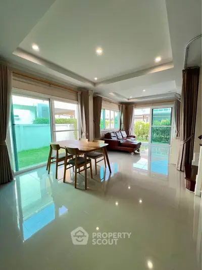 Spacious modern living room with large windows and elegant dining area