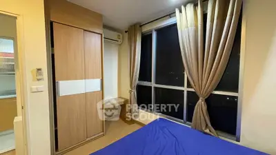 Cozy bedroom with large window and modern wardrobe, perfect for urban living.