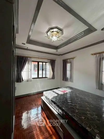 Spacious bedroom with elegant ceiling light and large windows for natural light.