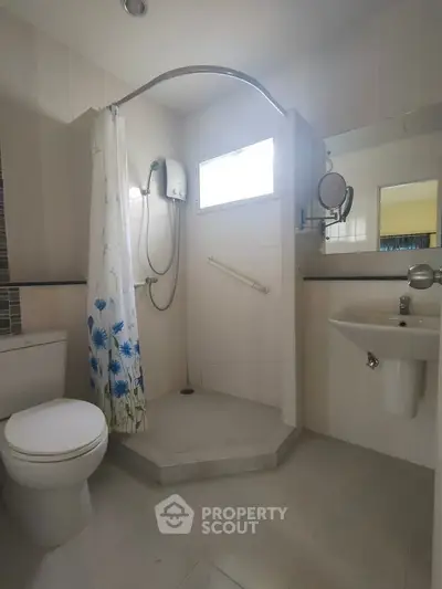 Spacious bathroom with modern shower and floral curtain