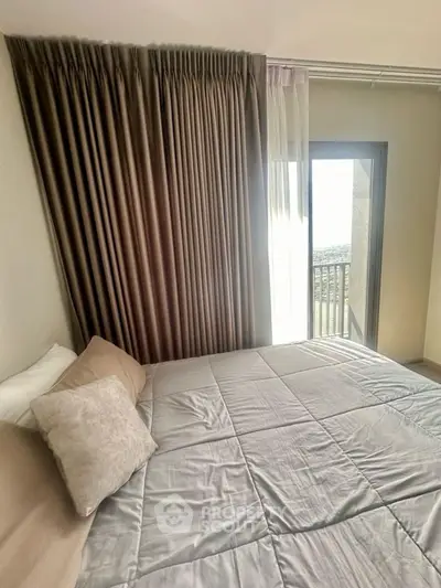 Cozy bedroom with elegant curtains and a comfortable bed, featuring a balcony view.