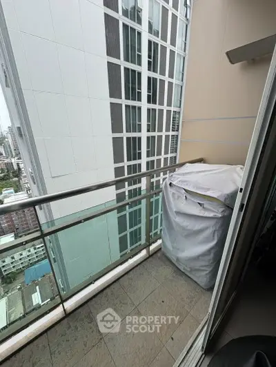 Compact balcony with city view and covered appliance, ideal for urban living.