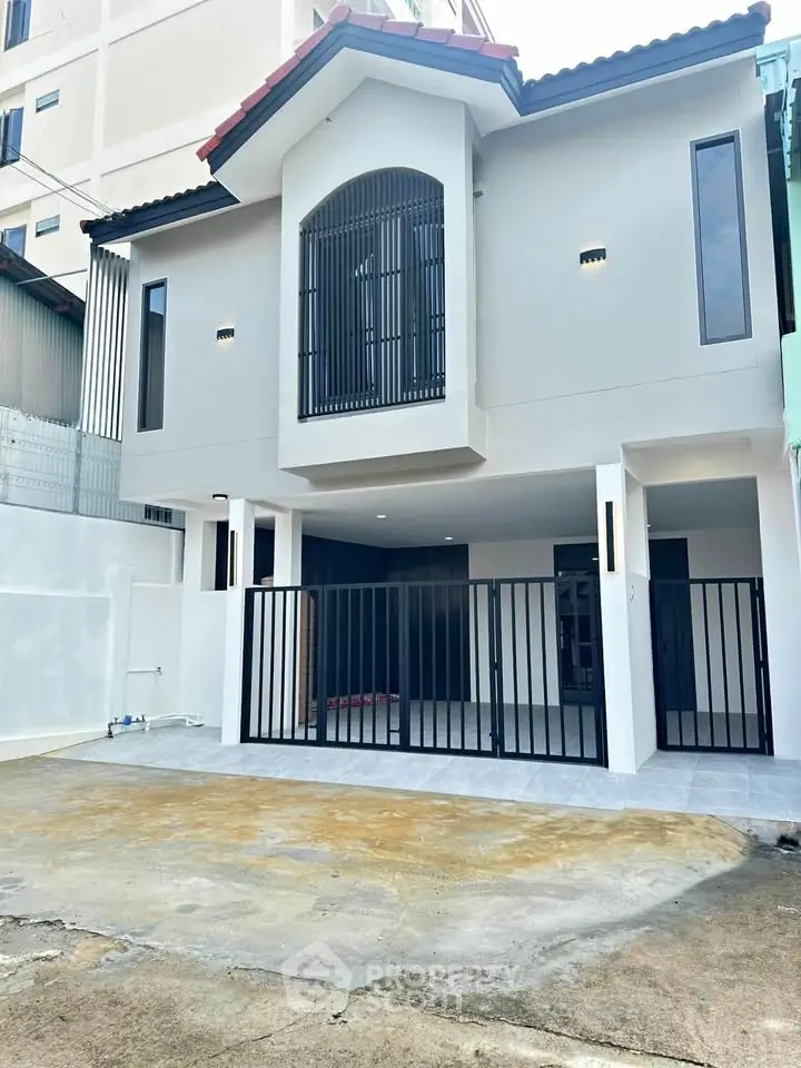 Modern two-story house with gated entrance and spacious driveway, perfect for urban living.