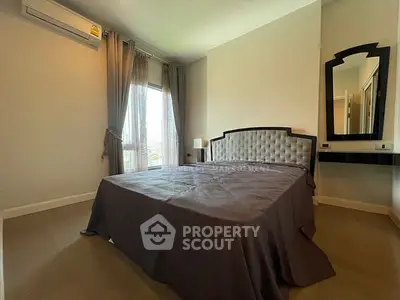 Spacious bedroom with elegant decor and large window offering natural light.