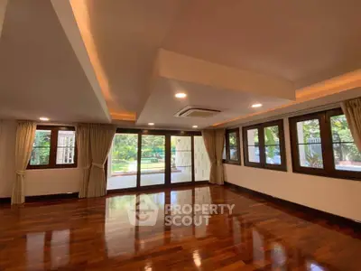 Spacious living room with wooden flooring and large windows overlooking garden