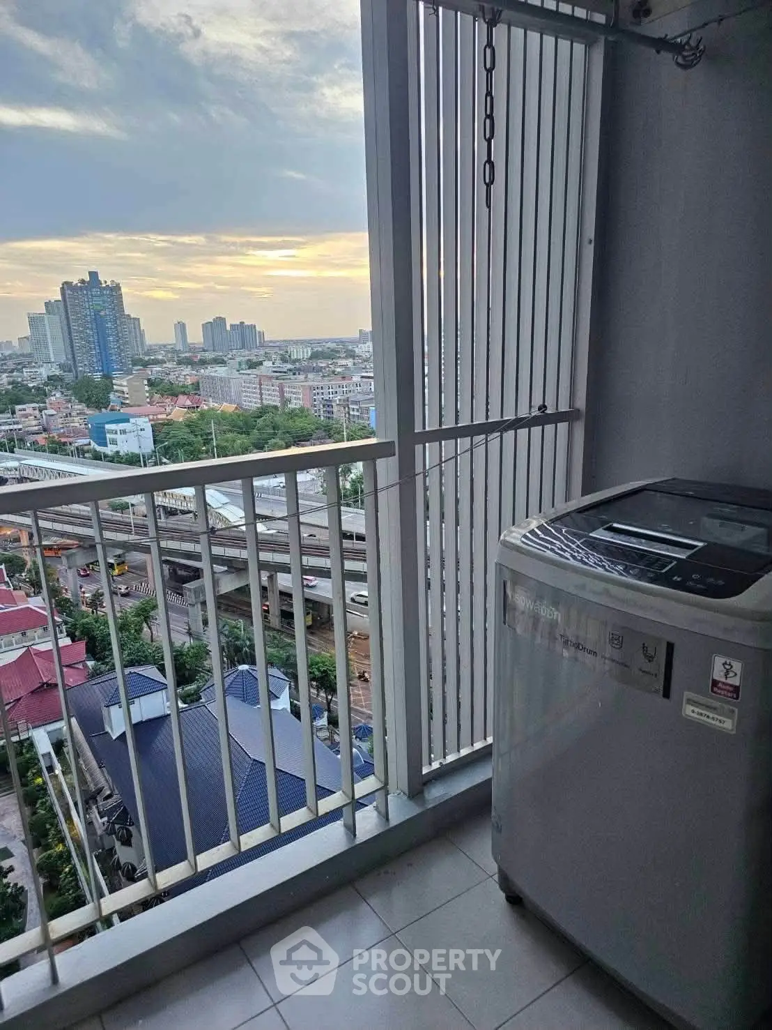 High-rise balcony with city view and washing machine, perfect for urban living.