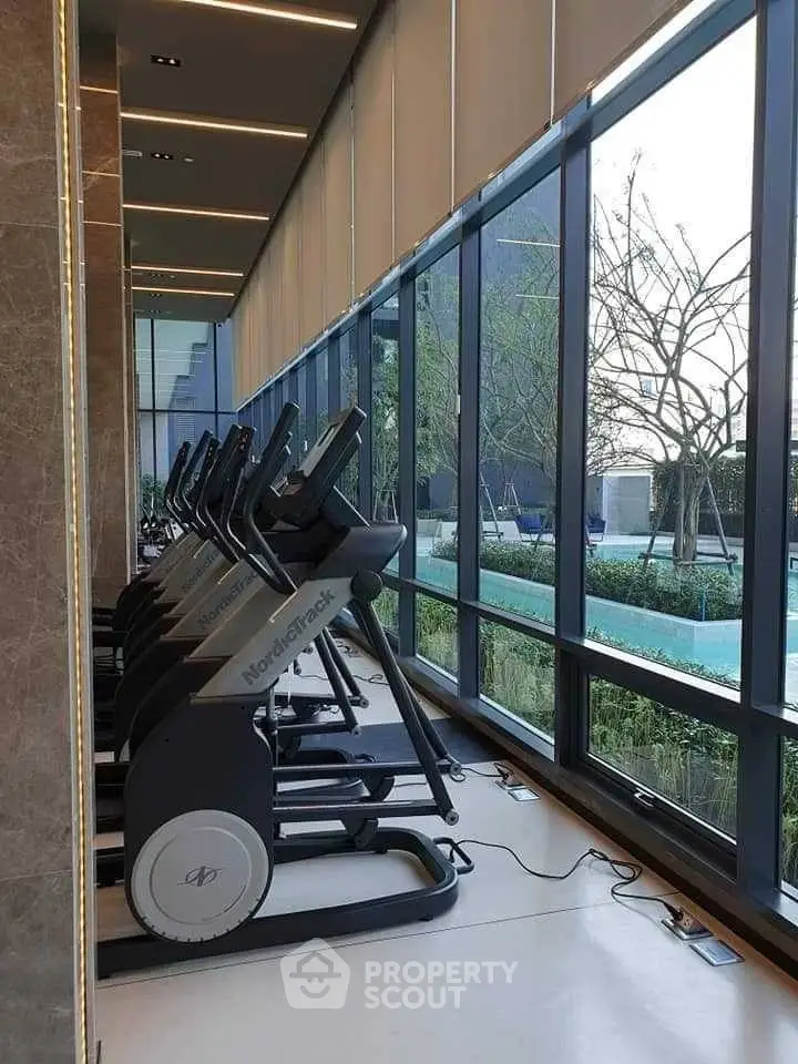 Modern gym with treadmills and large windows offering scenic outdoor views.