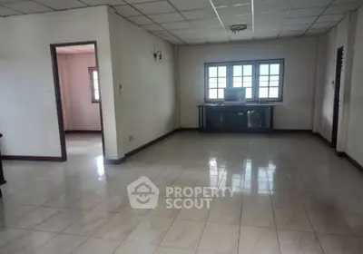 Spacious living room with tiled flooring and large windows in a residential property.