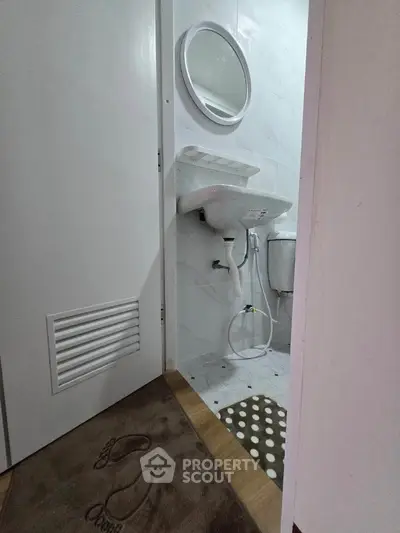Compact bathroom with round mirror and modern sink in cozy apartment.