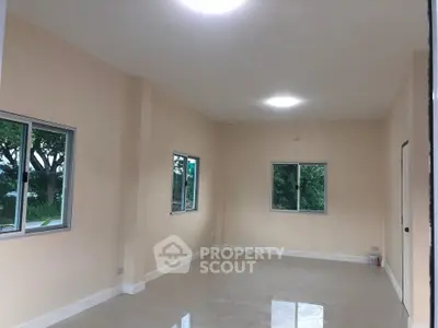 Spacious unfurnished room with large windows and glossy tiled floor, ideal for customization.