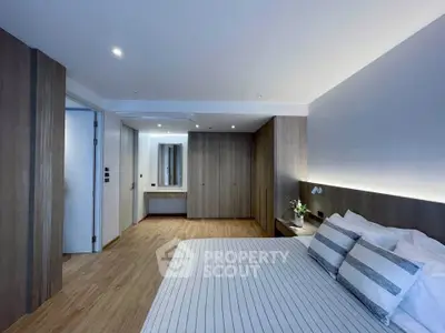 Modern bedroom with sleek design and wooden accents, featuring a comfortable bed and ample storage space.