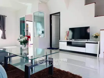 Modern living room with sleek glass table and TV unit, bright and inviting space.