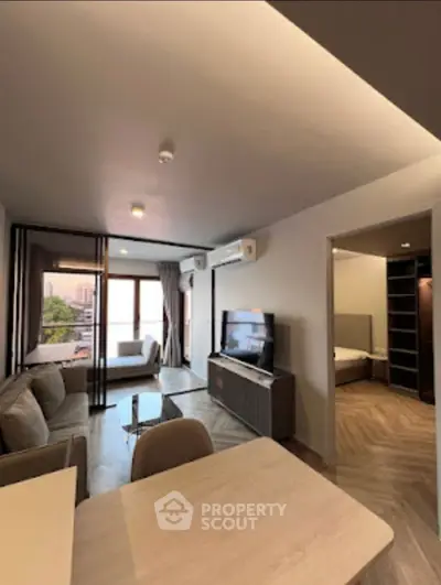 Modern living room with open layout and natural light, featuring a cozy sofa and sleek TV unit.