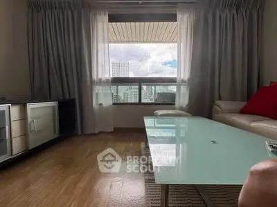 Modern living room with glass coffee table and city view through large window.