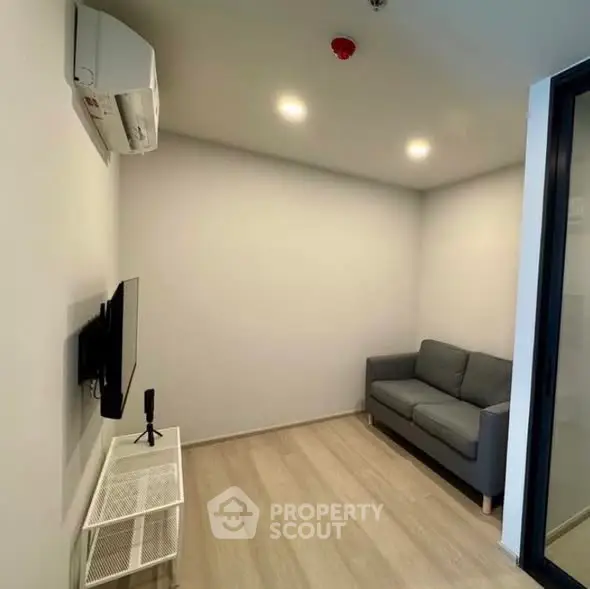 Cozy living room with modern sofa and wall-mounted TV in a compact space.