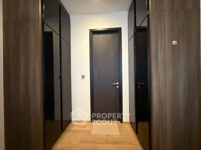 Modern hallway with sleek wooden doors and glossy black cabinets