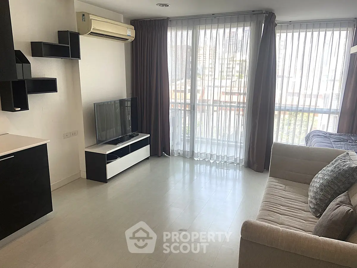 Modern living room with large windows and stylish furniture in a city apartment.