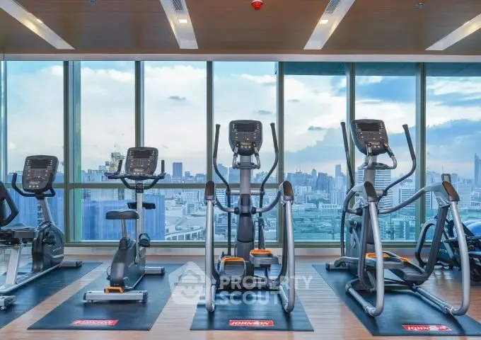 Modern gym with city view and state-of-the-art exercise equipment in high-rise building.