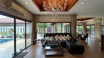 Luxurious living room with pool view and elegant chandelier in modern home.