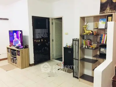 Cozy living room with TV and bookshelf, perfect for relaxation and entertainment.