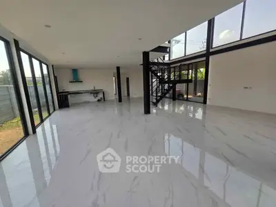 Spacious modern living room with large windows and sleek staircase in a contemporary home.