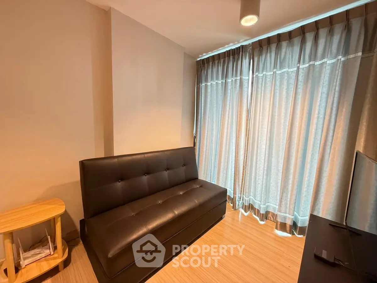 Cozy living room with modern sofa and floor-to-ceiling curtains, perfect for relaxation.
