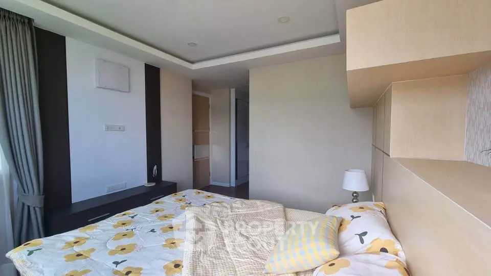 Cozy bedroom with floral bedding and modern design, featuring ample natural light and stylish decor.