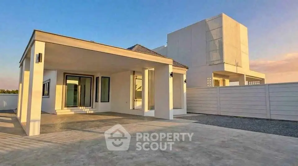 Modern minimalist house with sleek architecture and spacious driveway at sunset.