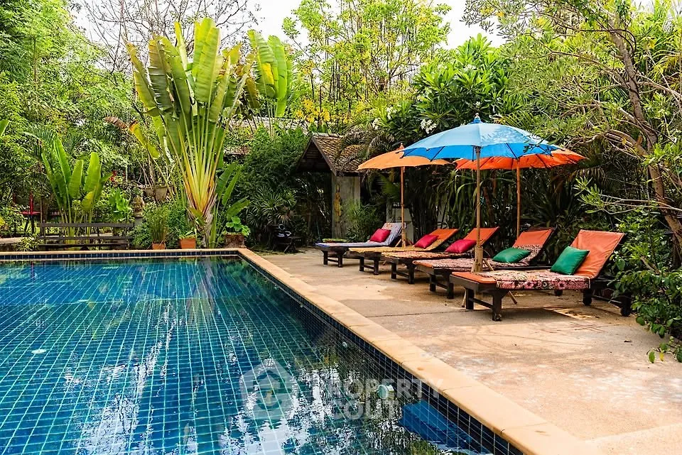 Luxurious outdoor pool area with lush greenery and colorful sun loungers, perfect for relaxation and leisure.