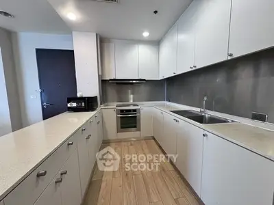 Modern kitchen with sleek cabinetry and built-in oven in a spacious apartment.