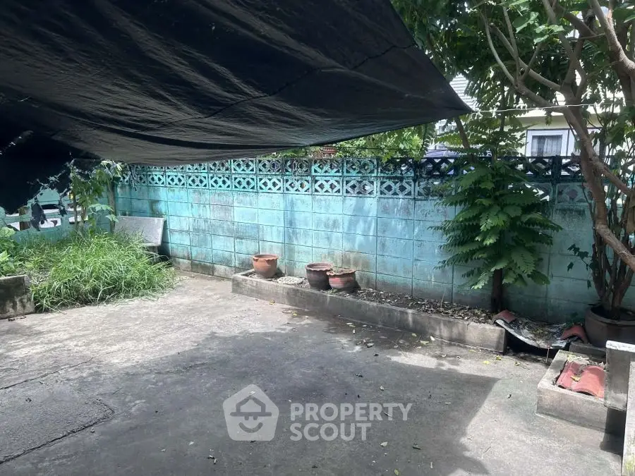 Spacious outdoor area with concrete flooring and lush greenery, ideal for gardening or outdoor activities.