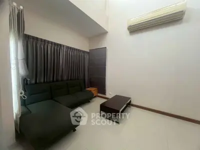 Modern living room with sleek black sofa and air conditioning unit