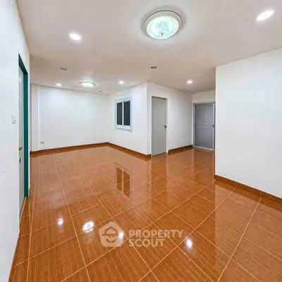 Spacious empty room with glossy brown tile flooring and modern ceiling lights.