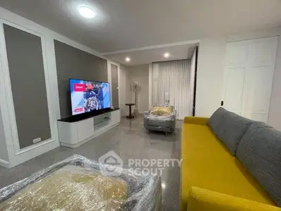 Spacious modern living room with stylish furniture and large TV, perfect for relaxation.