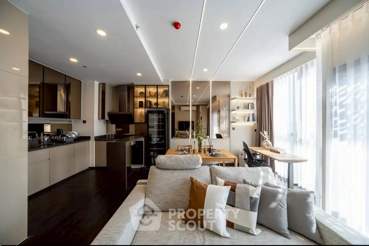 Luxurious modern living room with open kitchen and elegant decor, featuring ample natural light and stylish furnishings.