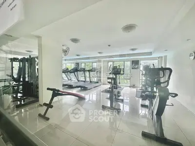 Spacious gym with modern equipment and large windows offering a refreshing view.
