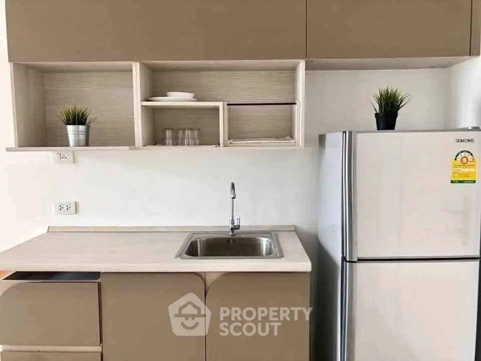 Modern kitchen with sleek cabinetry and stainless steel fridge in a stylish apartment.