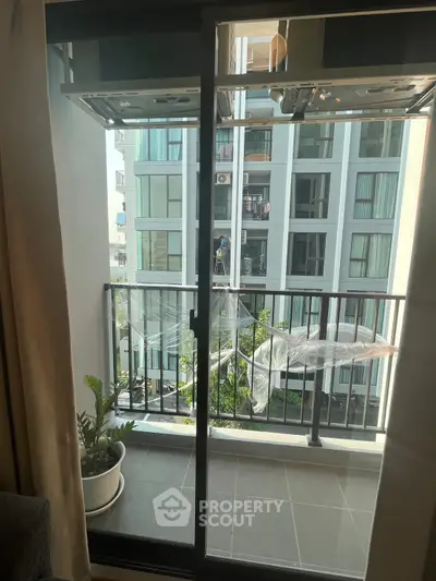 Modern apartment balcony with sliding glass doors and city view.
