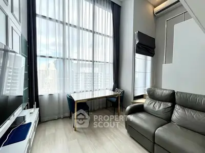 Modern living room with high ceilings and large windows offering city views.