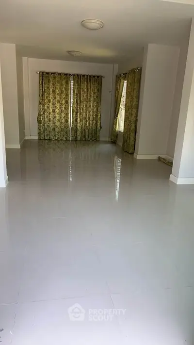 Spacious empty room with glossy tiled floors and floral curtains, ideal for customization.