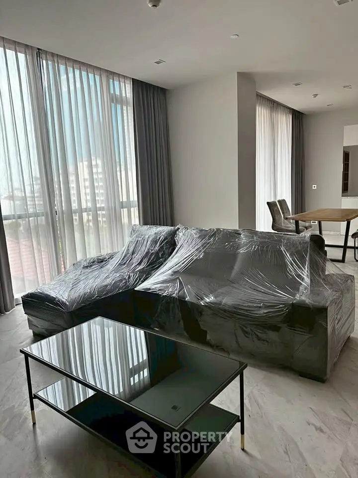 Spacious modern living room with large windows and elegant furniture, perfect for urban living.