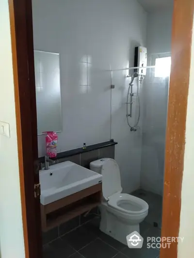 Compact modern bathroom with wall-mounted sink, toilet, and glass shower enclosure, ideal for efficient living spaces.