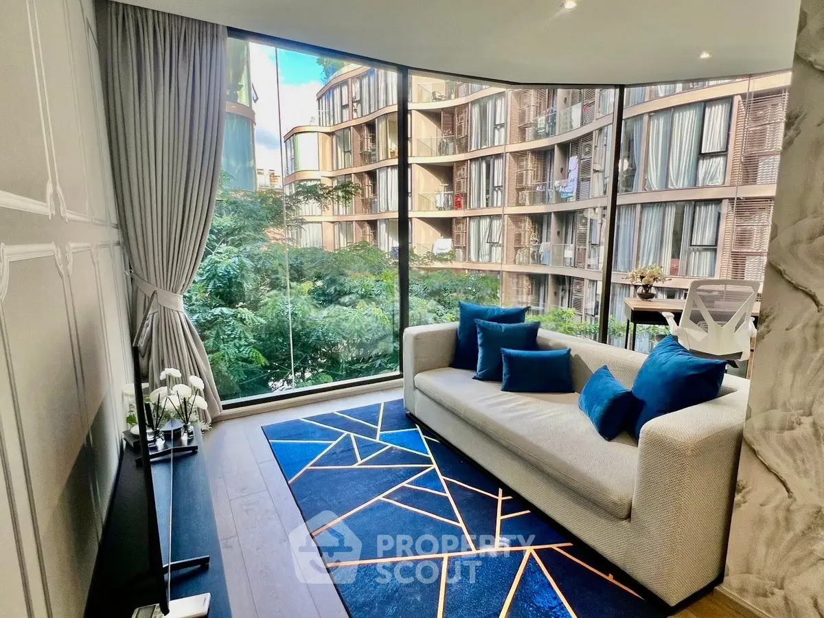 Modern living room with large windows and stylish decor overlooking lush greenery.