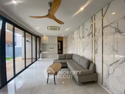 Luxurious modern living room with marble walls and sleek furniture, featuring a stylish ceiling fan and large sliding glass doors.