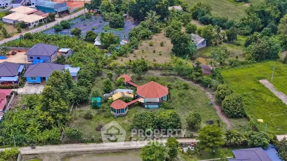 Aerial view of a charming countryside property with lush greenery and a unique architectural design.