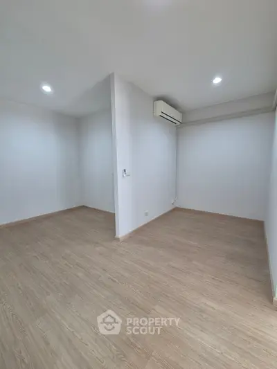 Spacious minimalist room with wooden flooring and air conditioning, perfect for modern living.